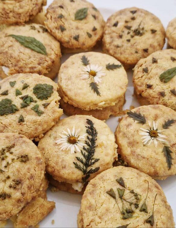 Runde Kekse, verziert mit gepressten weißen Blüten und grünen Blättchen
