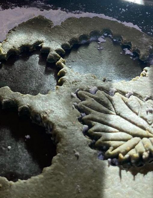 Blattförmige Laubmehl-Plätzchen mit eingeprägten Blattadern und Zuckerstreuseln auf dem Blech